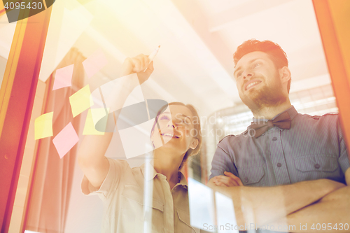 Image of happy creative team writing on blank office glass