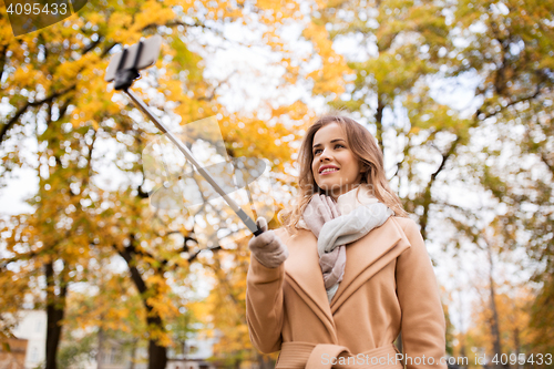 Image of woman taking selfie by smartphone in autumn park