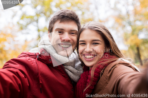 Image of happy young couple taking selfie in autumn park