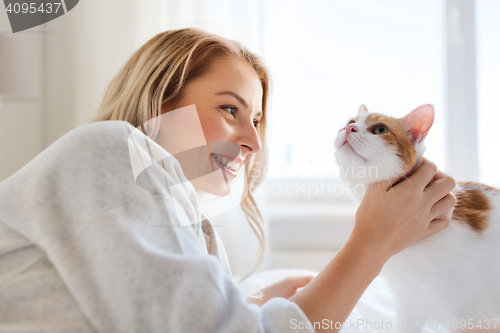 Image of happy young woman with cat in bed at home