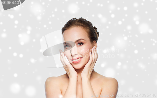 Image of beautiful young woman touching her face over snow