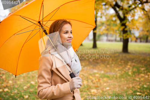 Image of happy woman with umbrella walking in autumn park