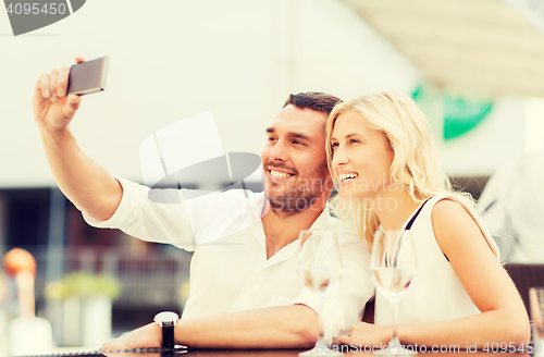 Image of happy couple taking selfie with smartphone at cafe