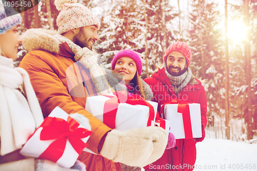 Image of happy friends with gift boxes in winter forest