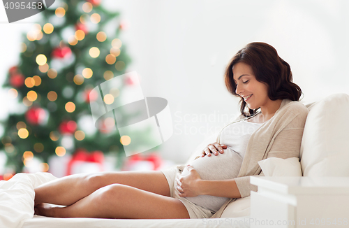 Image of happy pregnant woman lying on bed at christmas