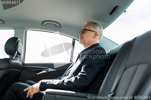 Image of senior businessman driving on car back seat