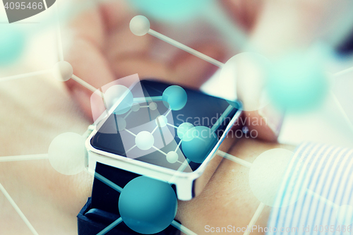 Image of close up of hands with molecules on smartwatch