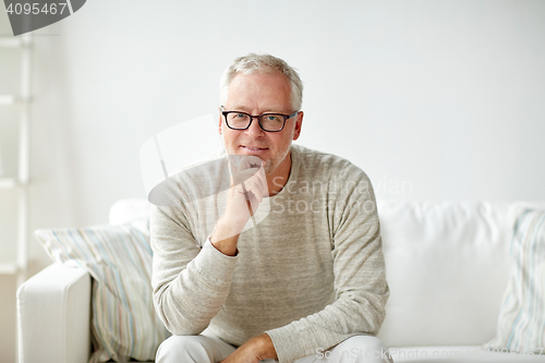 Image of smiling senior man in glasses sitting on sofa