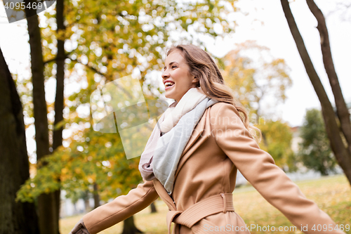 Image of beautiful happy young woman walking in autumn park