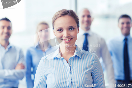 Image of smiling businesswoman with colleagues in office