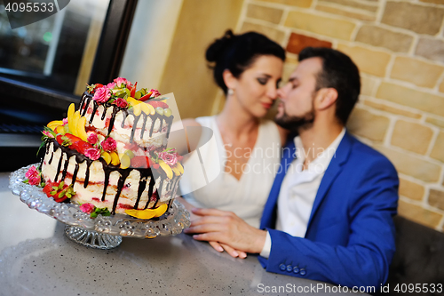 Image of bride and groom kissing on the background of a wedding cake