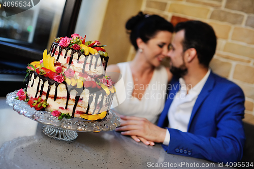 Image of bride and groom kissing on the background of a wedding cake