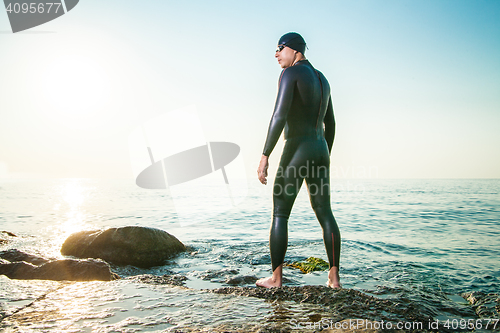 Image of Man in diving suit standing in waves