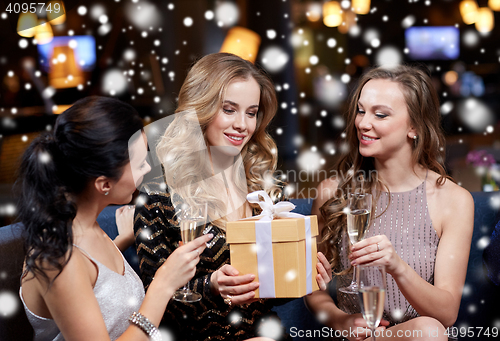 Image of happy women with champagne and gift at night club