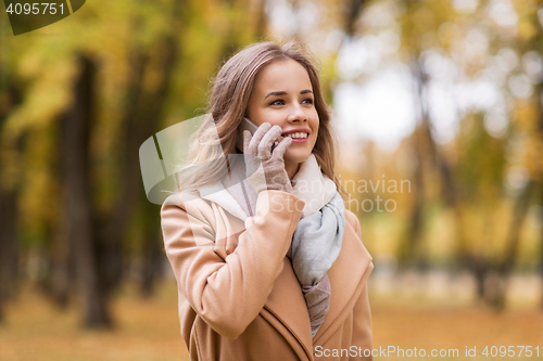 Image of woman calling on smartphone in autumn park