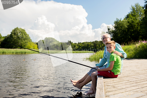 Image of grandfather and grandson fishing on river berth