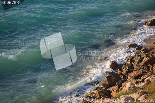 Image of Rocky cliff and lazy lapping turquoise waves