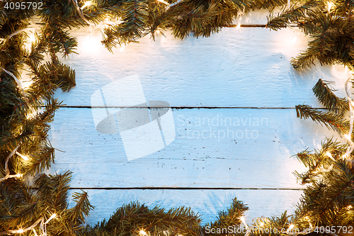 Image of Christmas wooden background with fir-tree branches and lightbulb