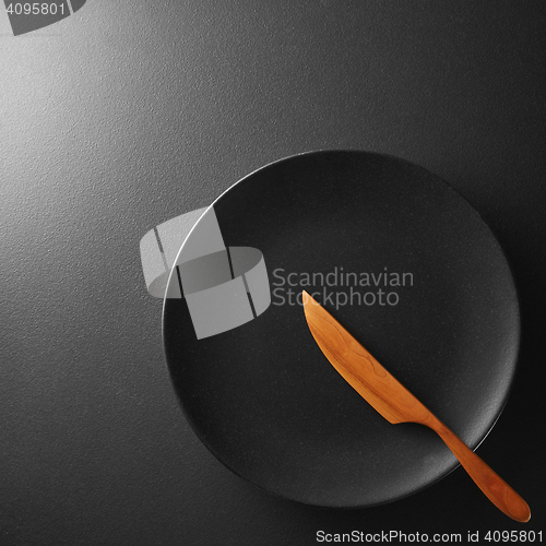 Image of Black plate with knife on a background.