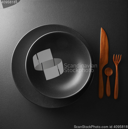 Image of serving of black table with dark wooden utensils and cutlery