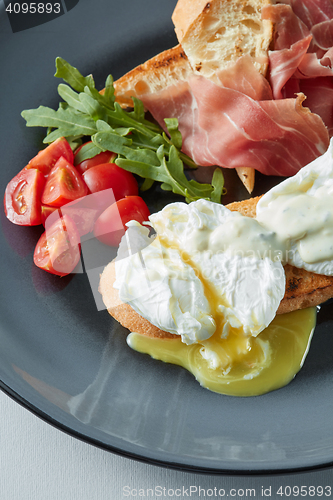 Image of Eggs Benedict with bacon, toast and salad.