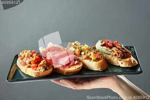 Image of delicious variety of Italian bruschetta on a ceramic tray