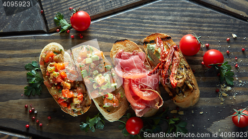 Image of Various of mini bruschetta with tomatoes, salmon, avocado, bacon, and basil butter