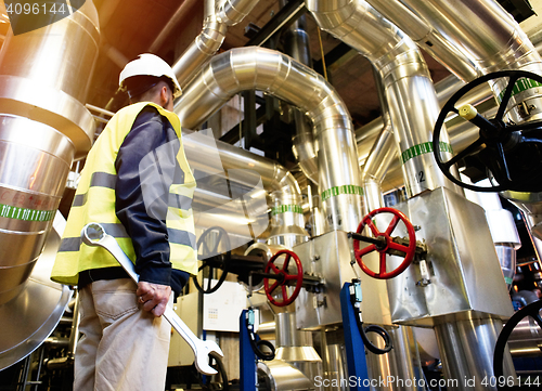 Image of industrial worker with spanner at factory workshop