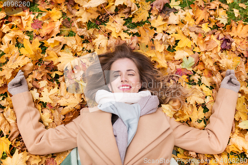 Image of beautiful happy woman lying on autumn leaves