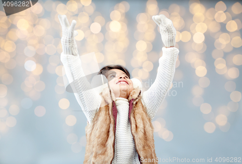 Image of happy little girl wearing earmuffs over lights