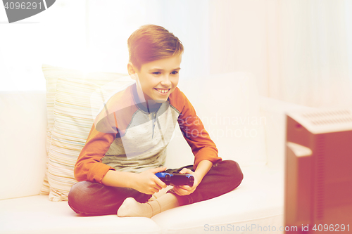 Image of happy boy with joystick playing video game at home