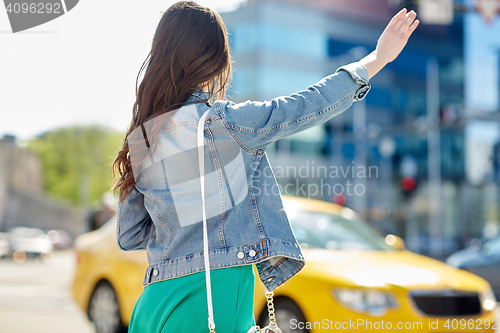 Image of young woman or girl catching taxi on city street