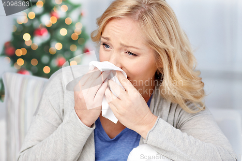 Image of ill woman blowing nose to paper napkin