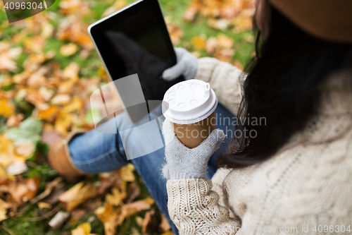 Image of woman with tablet pc and coffee in autumn park