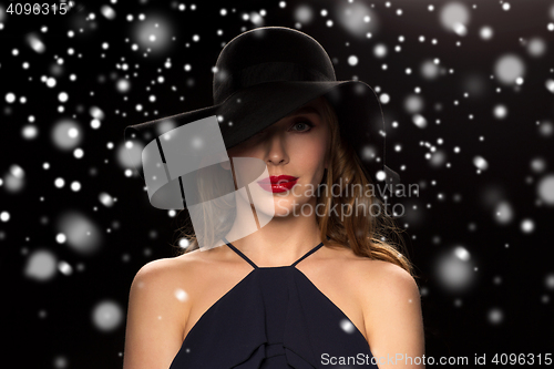 Image of beautiful woman in black hat over snow