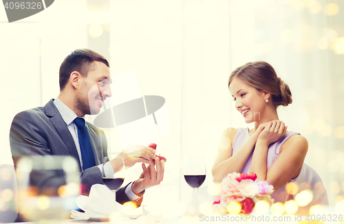 Image of man proposing to his girlfriend at restaurant