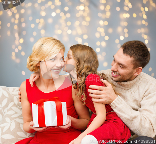 Image of happy family with christmas gift kissing