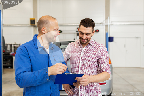 Image of auto mechanic with clipboard and man at car shop