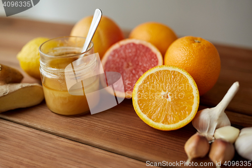 Image of honey, citrus fruits, ginger and garlic on wood