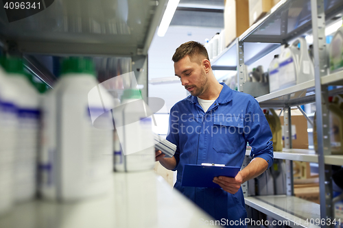 Image of auto mechanic with oil and clipboard at car shop