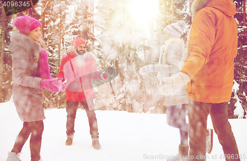 Image of happy friends playing with snow in winter forest