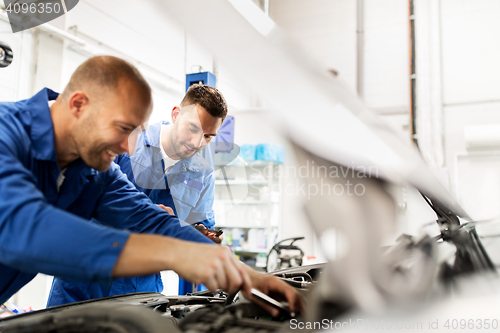 Image of mechanic men with wrench repairing car at workshop