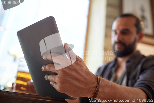 Image of close up of man with tablet pc and beer at pub