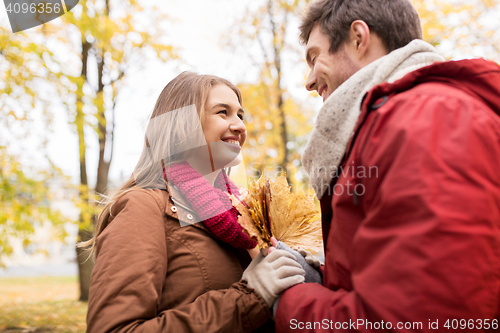 Image of happy couple with maple leaves in autumn park