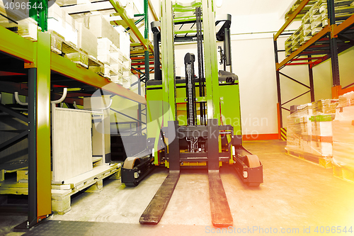 Image of Forklift, shelves and racks with pallets in distribution warehou