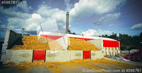 Image of bio power plant with storage of wooden fuel against blue sky