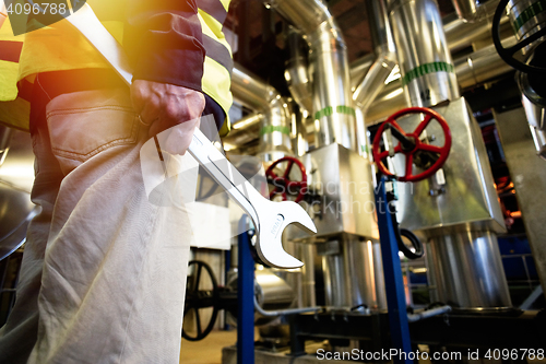 Image of industrial worker with spanner at factory workshop