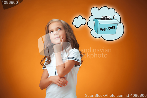 Image of The cute thoughtful little girl on orange background