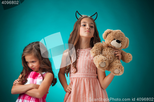 Image of The two cute little girls on blue background with Teddy bear