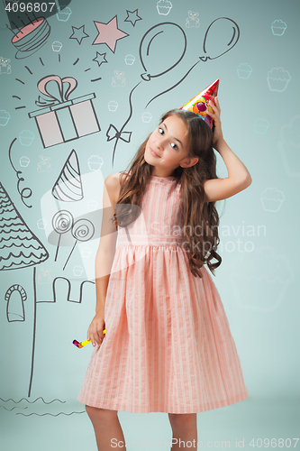 Image of The cute cheerful little girl with festive cap on gray background